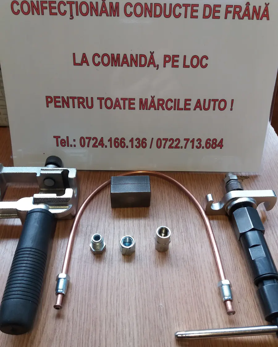 Afișul „Confecționăm conducte de frână la comandă, pe loc” lângă sculele de bordurat